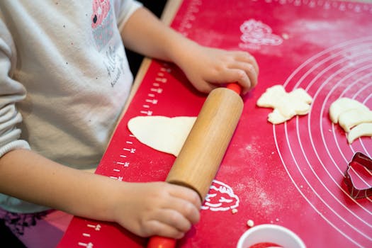 Un enfant roule de la pâte à biscuits sur un plan de travail avec des emporte-pièces en forme d'animaux.