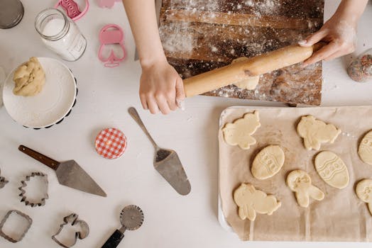 Préparation de sablés en famille avec pâte étalée et emporte-pièces sur une table de cuisine.