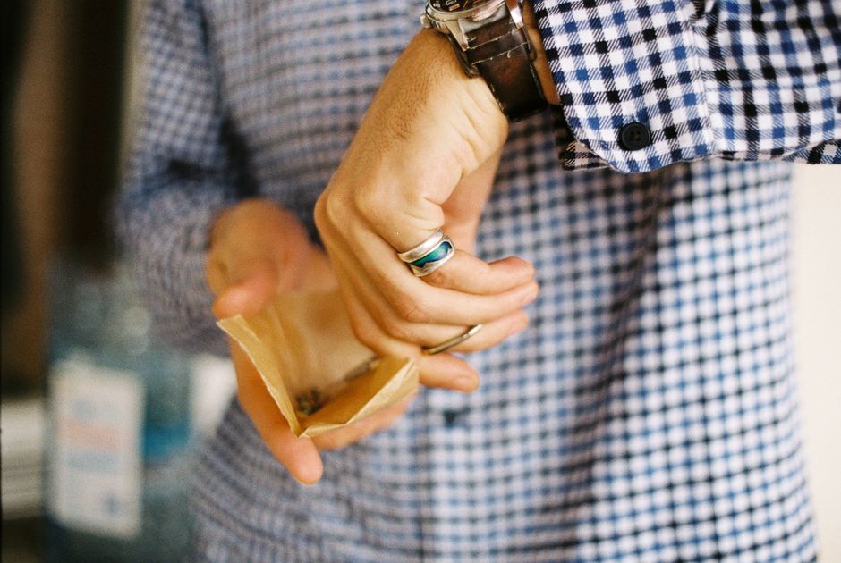 Homme en chemise à carreaux tenant une petite enveloppe tout en portant plusieurs bagues.